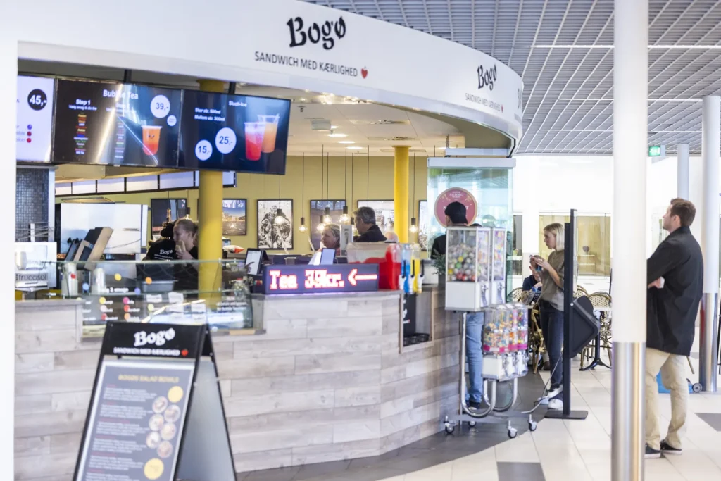 Facaden af Bogø Sandwich spisested i Shoppen Aalborg med kunder og menukort.
