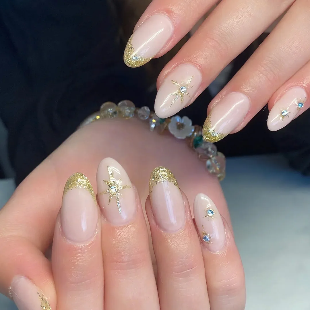Elegante negle med guld glimmer og stjerne detaljer lavet hos Nordic Nails og Spa.